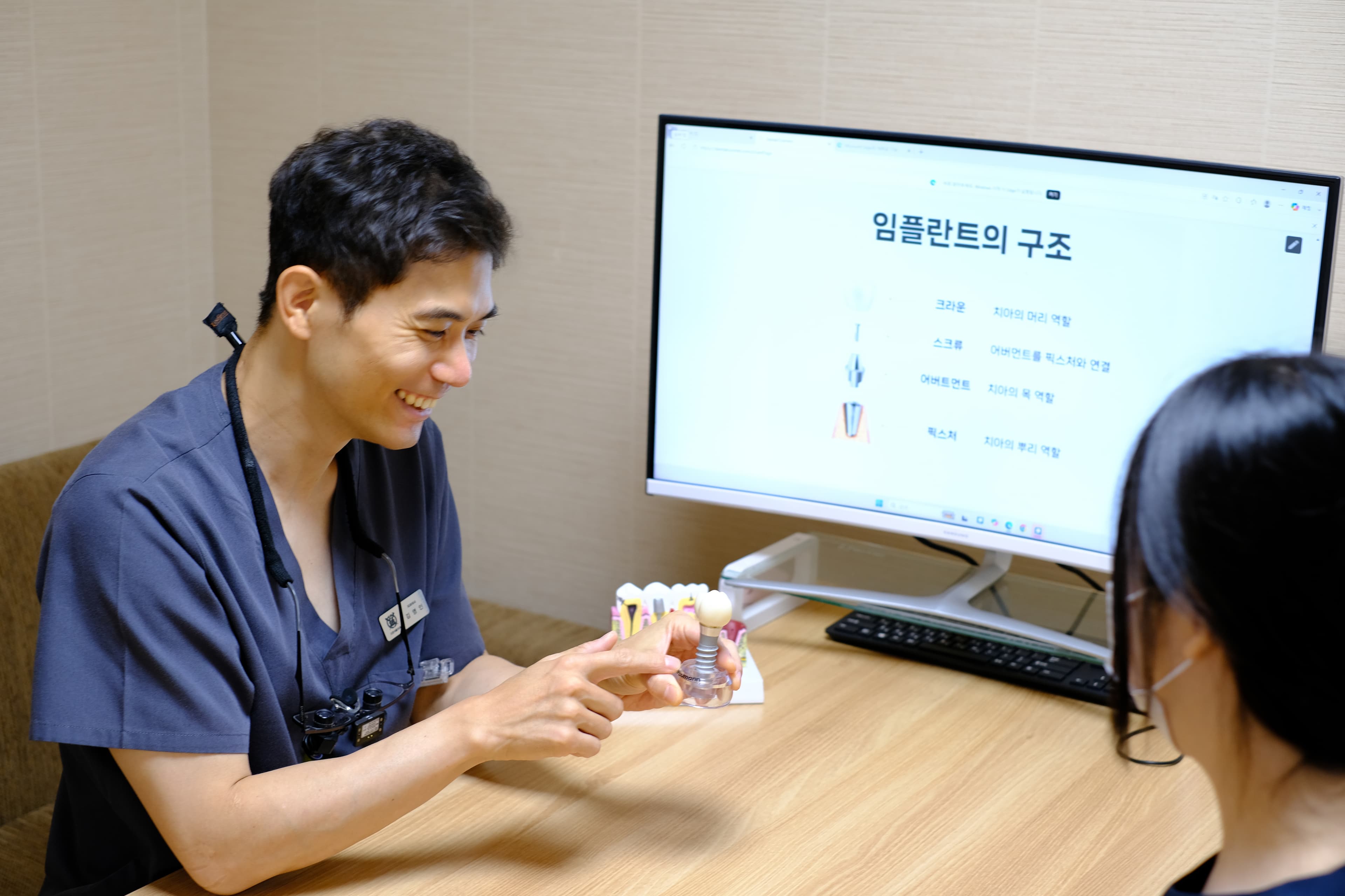 임플란트 모형을 들고 환자와 상담하는 김영인 대표원장